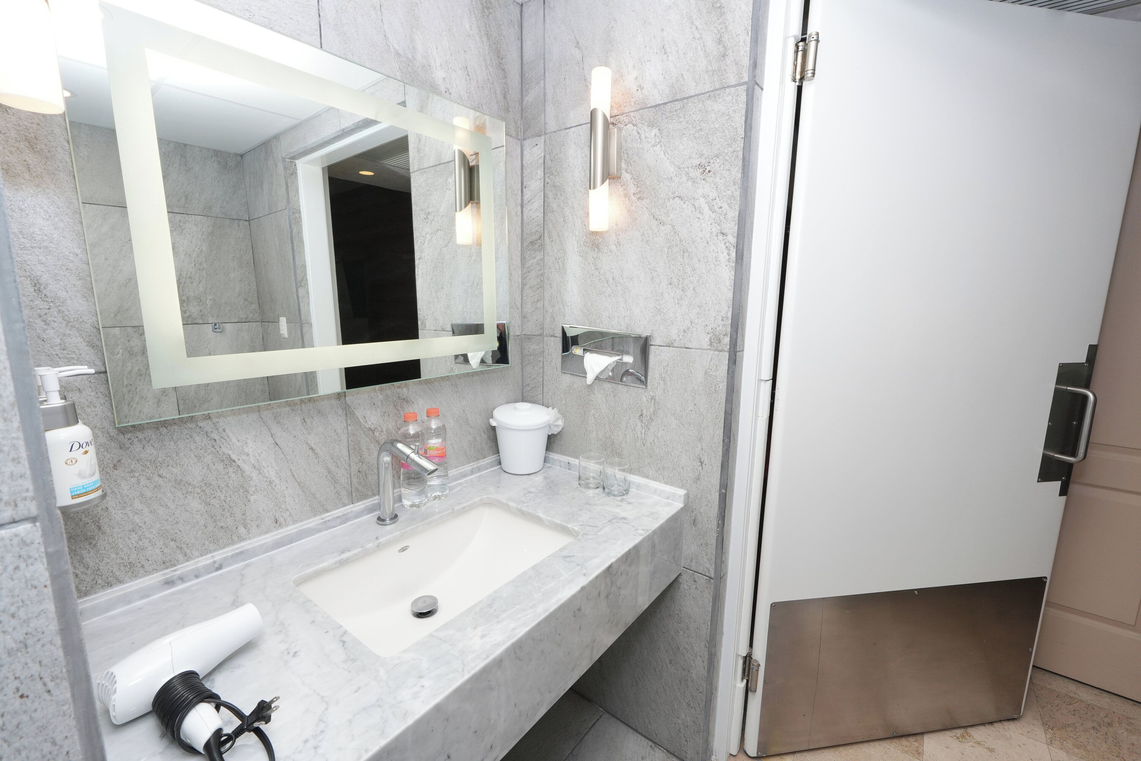 A modern bathroom with a marble sink, a large mirror, and a shower area.
