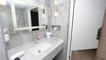 A modern bathroom with a marble sink, a large mirror, and a shower area.