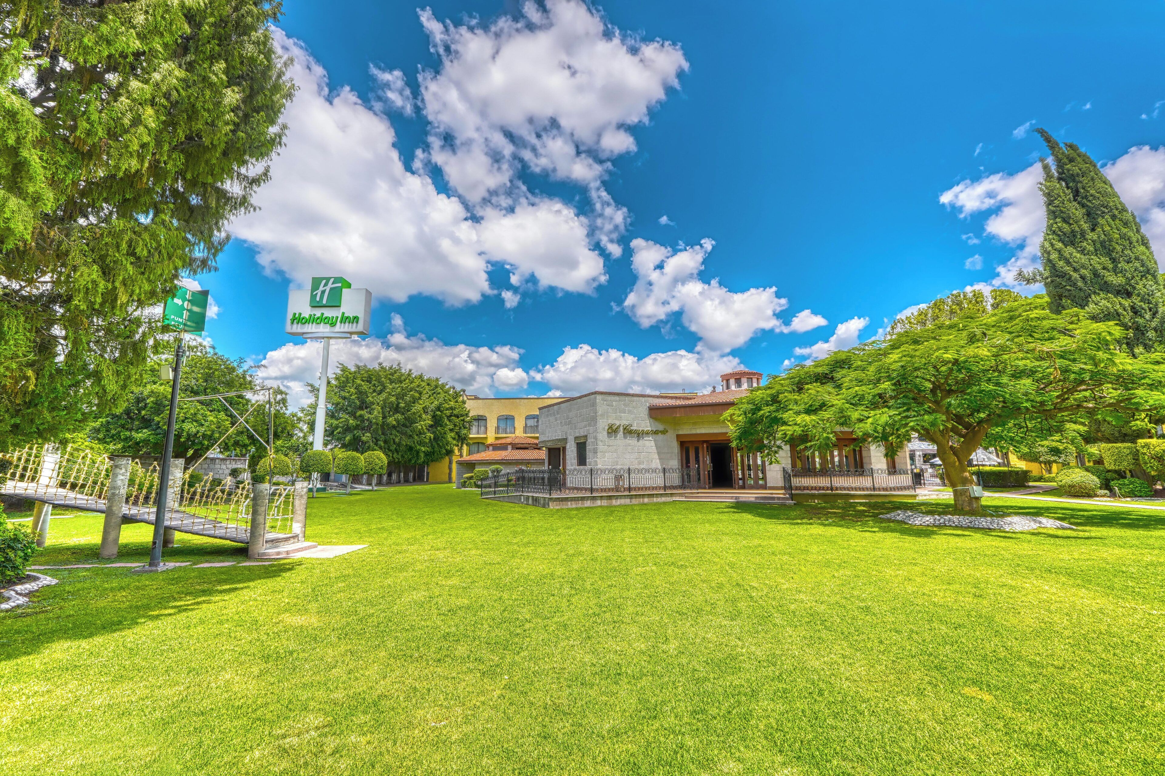 Señal de Holiday Inn, un edificio de piedra y un césped bien cuidado.
