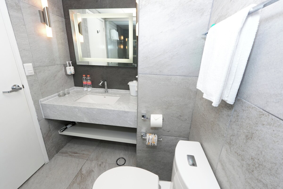 A modern bathroom with a large mirror, a sink, and a toilet.