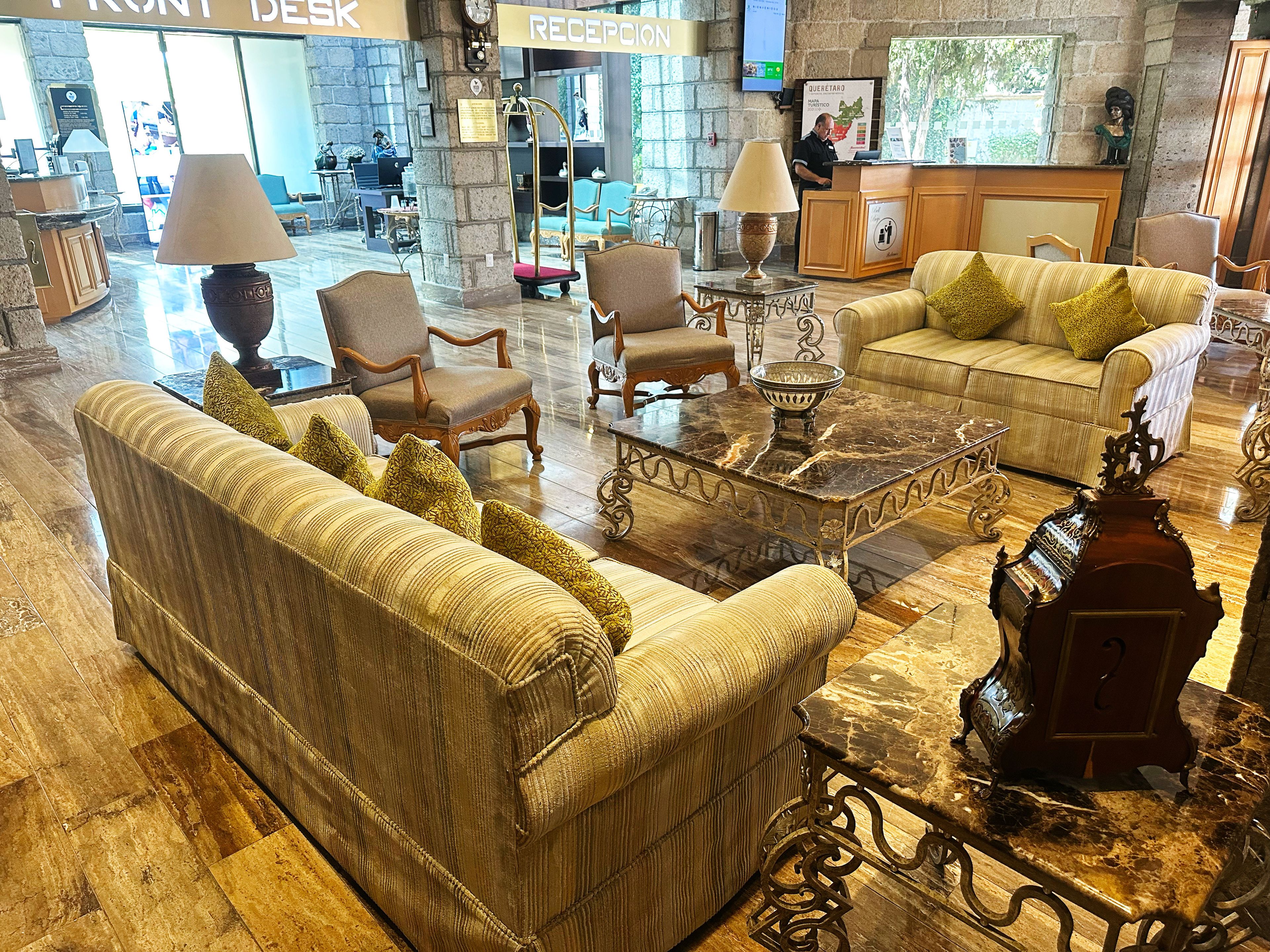 A lobby with a reception desk, seating area with sofas and armchairs, a coffee table, and a decorative vase.