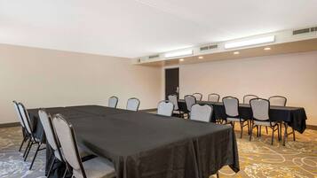 Una sala de conferencias con una larga mesa y sillas, piso alfombrado y una puerta al fondo.