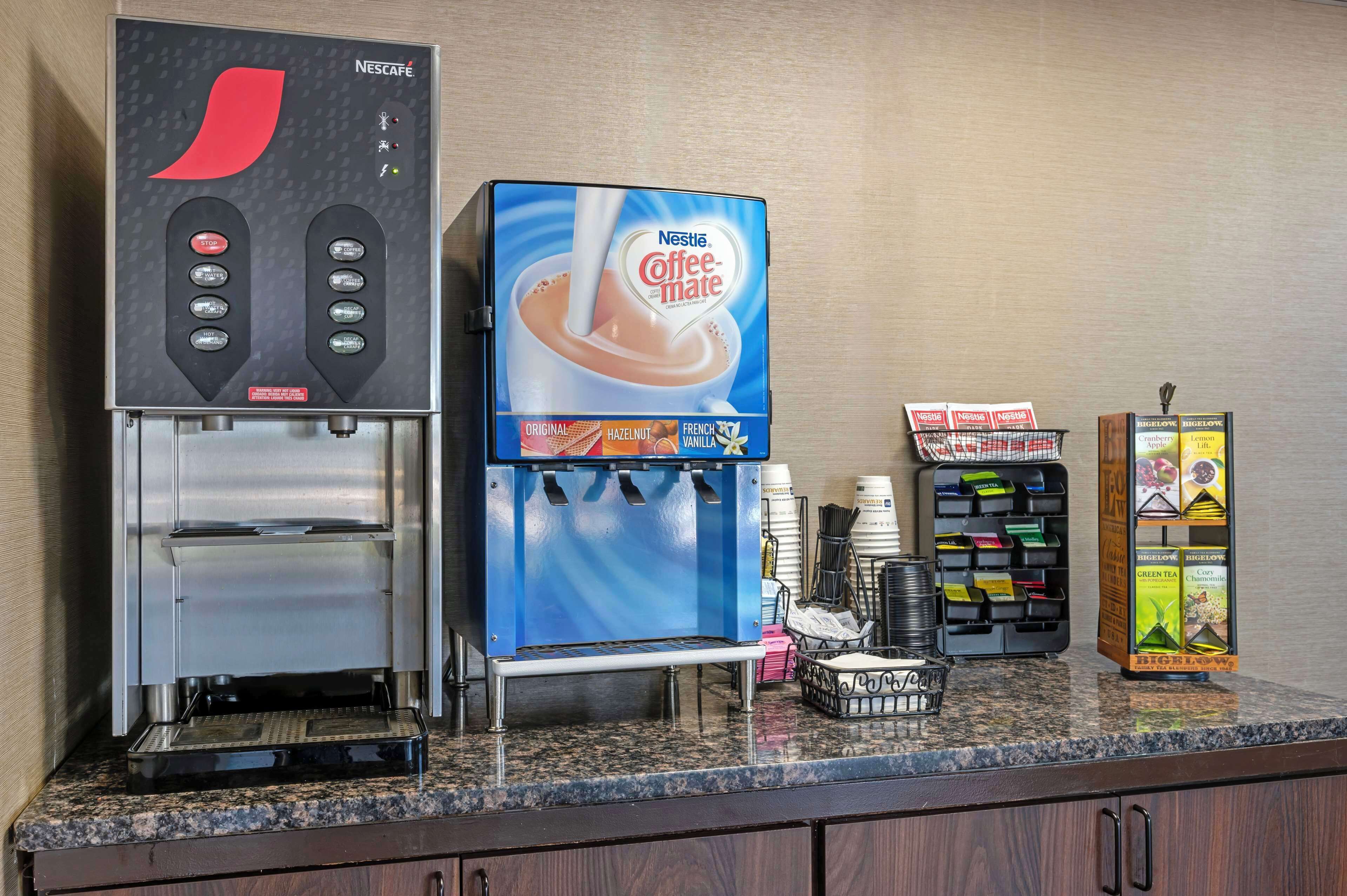Una cafetera con diseño azul y rojo, un dispensador de café y una selección de cápsulas de café sobre la encimera.