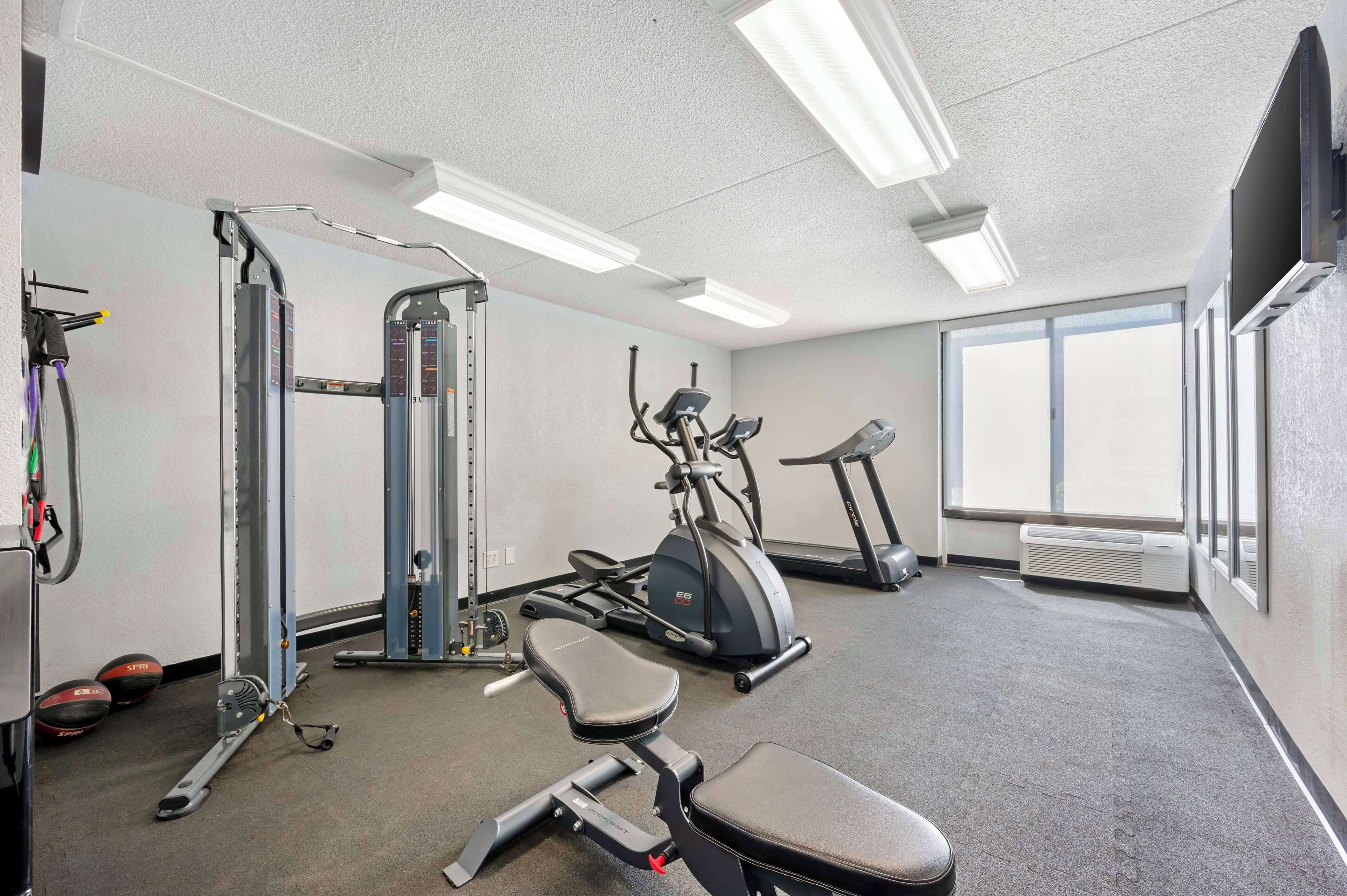 A gym with exercise equipment, a treadmill, and a large window providing natural light.