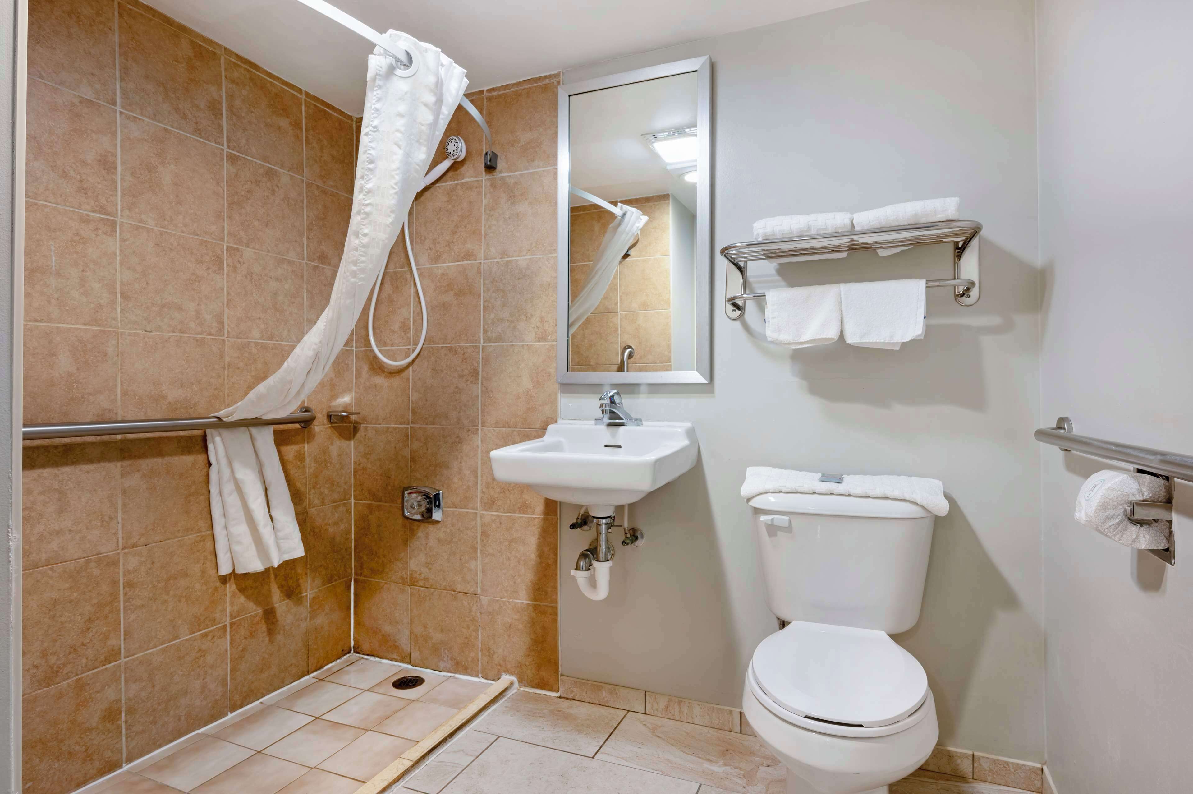 A bathroom with a shower, sink, toilet, and towel rack.
