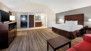 A hotel room with a large bed, a desk, a TV, and a bathroom visible through an open door. - Best Western Ashbury Inn (La Grange)