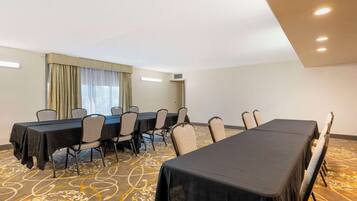 Uma sala de conferências com uma mesa comprida, cadeiras e uma janela grande com cortinas.