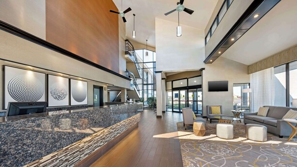 A spacious lobby with a reception desk, seating area, and a staircase leading to upper floors. - Best Western Ashbury Inn (La Grange)