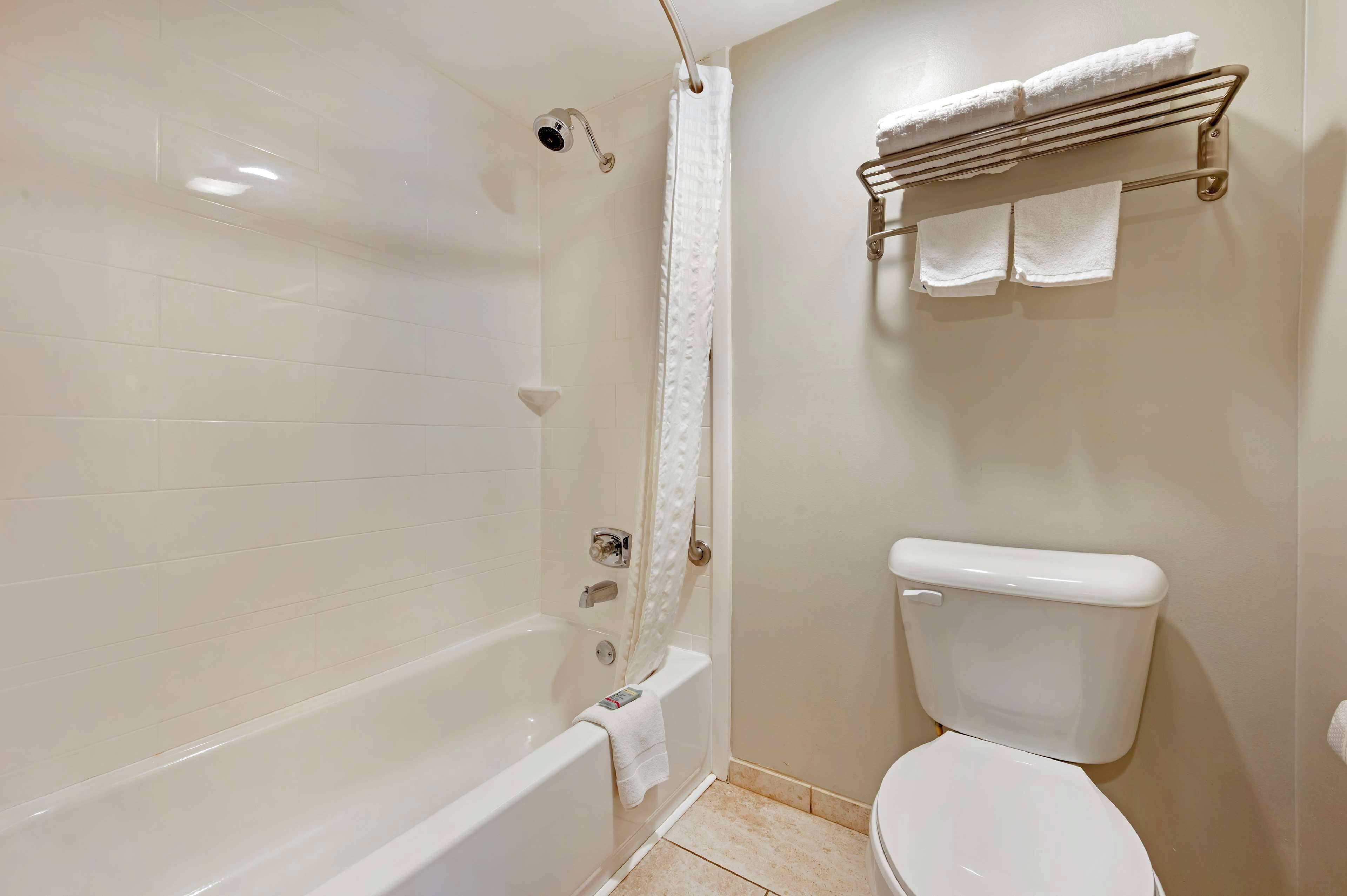 A bathroom with a bathtub, toilet, and a towel rack.