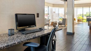 A modern hotel room with a desktop computer, a chair, and a view of the outdoor seating area. - Best Western Ashbury Inn (La Grange)