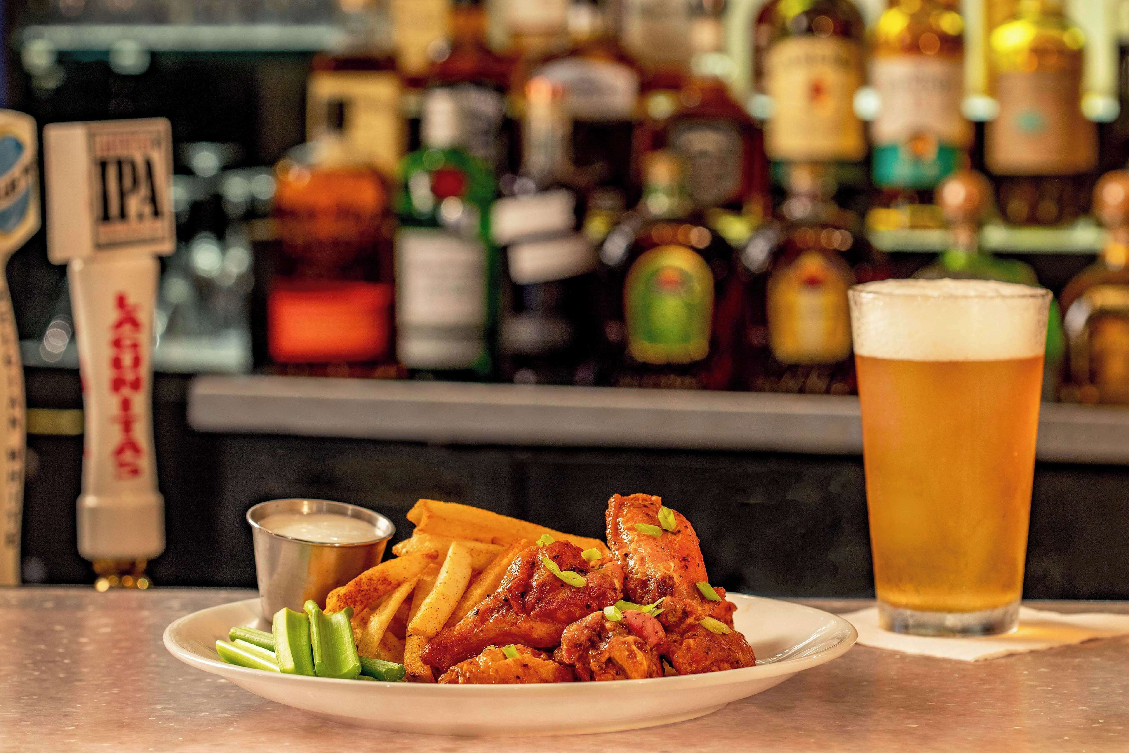 A plate of fried chicken with gravy, a glass of beer, and a small bowl of sauce on a table.