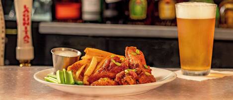 A plate of fried chicken with gravy, a glass of beer, and a small bowl of sauce on a table.