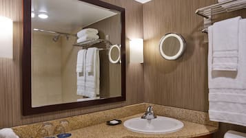 Un baño con un espejo grande, un lavabo y un perchero para toallas.