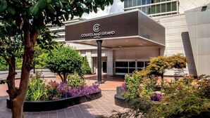 The Courtyard and Grand Hotel entrance with a modern design, surrounded by landscaped gardens and a variety of plants. - Courtland Grand Hotel, Trademark Collection by Wyndham (Atlanta)