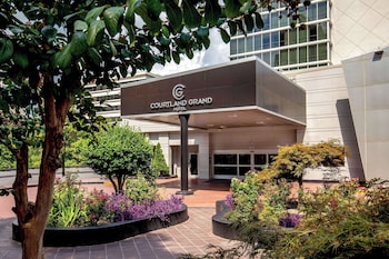 A Courtyard & Grand Hotel entrance with a landscaped garden and a well-maintained lawn. at Courtland Grand Hotel, Trademark Collection by Wyndham