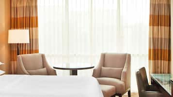 A hotel room with a bed, two armchairs, a small round table, and a lamp.