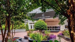A Courtyard & Grand Hotel entrance with a landscaped garden and a well-maintained lawn. - Courtland Grand Hotel, Trademark Collection by Wyndham (Atlanta)