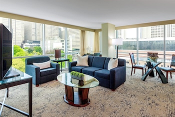 A hotel room with a large bed, a desk, a chair, a TV, and a window with a city view. at Courtland Grand Hotel, Trademark Collection by Wyndham