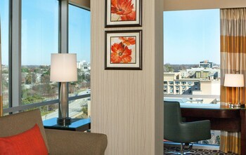 A conference room with rows of chairs, a stage with a screen, and large windows. at Courtland Grand Hotel, Trademark Collection by Wyndham