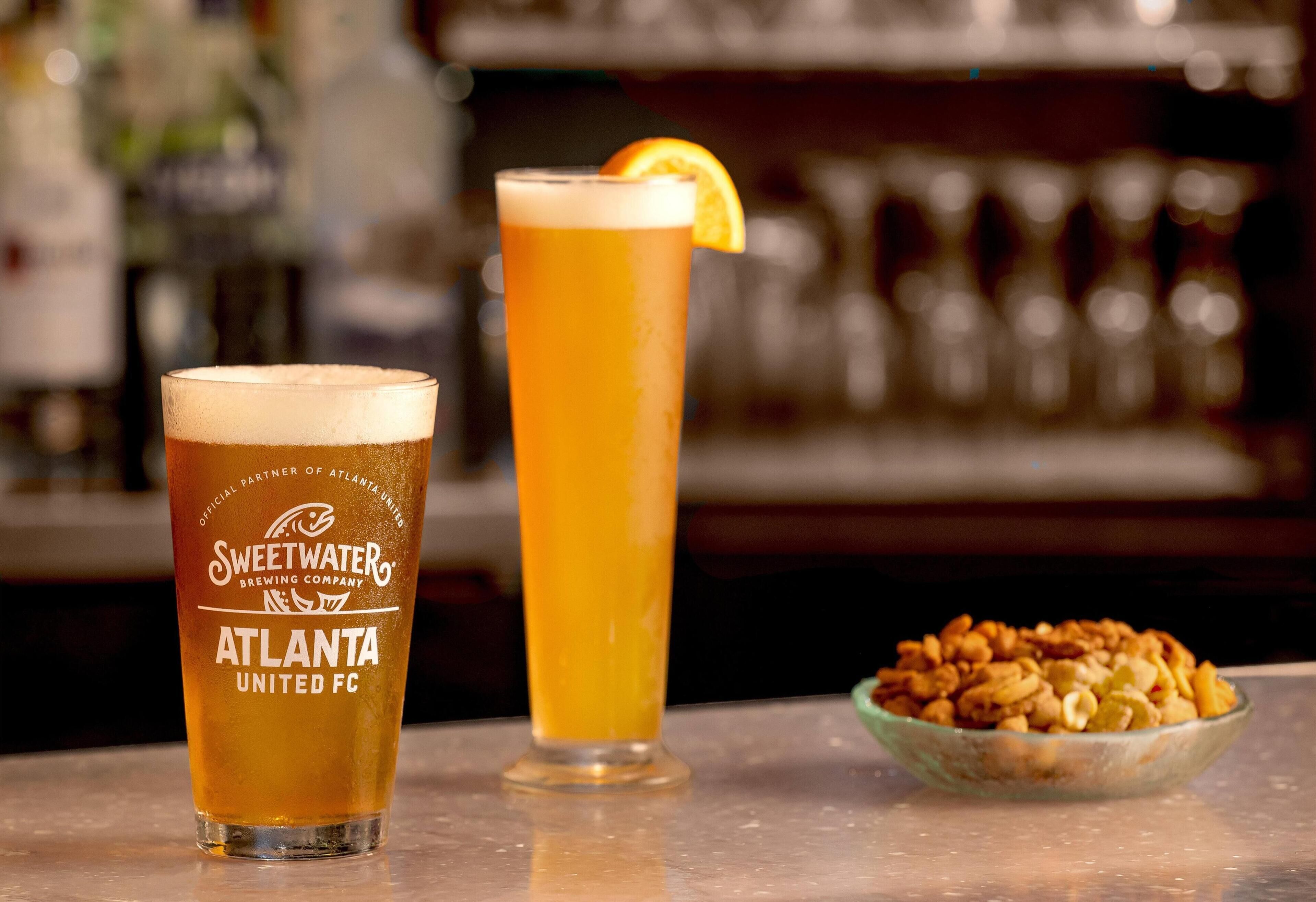Zwei Biergläser auf einer Theke, eines mit dem Aufdruck 'Sweetwaters Brewing Company Atlanta United FC'.
