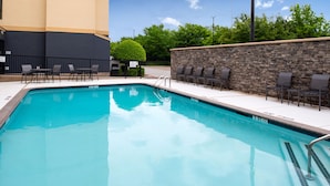 A swimming pool with lounge chairs and a stone wall. - Fairfield Inn & Suites by Marriott Arlington Six Flags (Arlington)