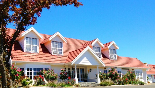 Stunning two-story building with a red-tiled roof and white trim, surrounded by beautifully maintained gardens.