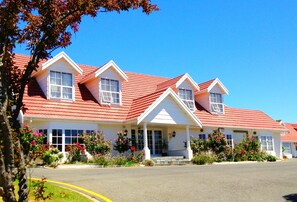 Classic hotel with a central entrance and two wings, surrounded by beautifully maintained gardens.