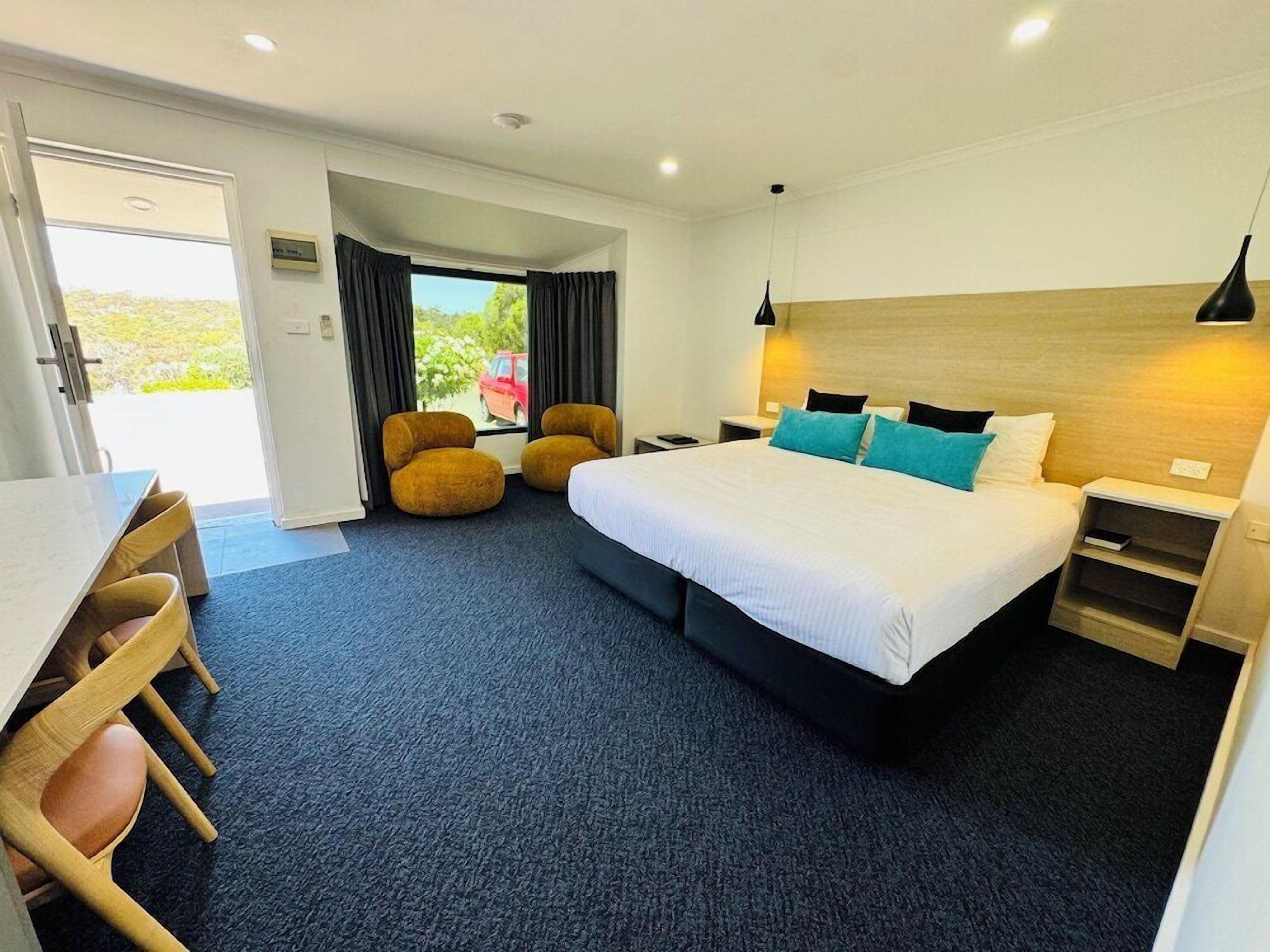 Une chambre d’hôtel équipée d’un lit, d’un bureau, d’une chaise, d’un canapé et offrant une vue sur l’extérieur.