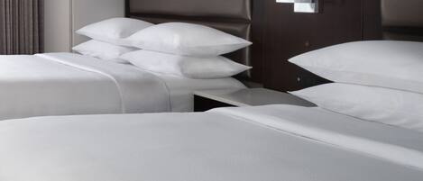 Una habitación de hotel moderna con una cama grande, una cama más pequeña y una mesita de noche con una lámpara.