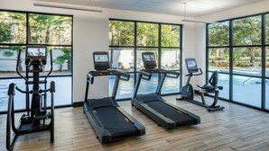 Un gimnasio con cintas de correr, elípticas y una máquina de remo.