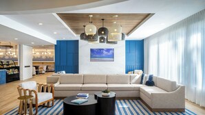 Una sala de estar moderna con un sofá modular, una mesa de centro redonda y una zona de comedor con mostrador y sillas.
