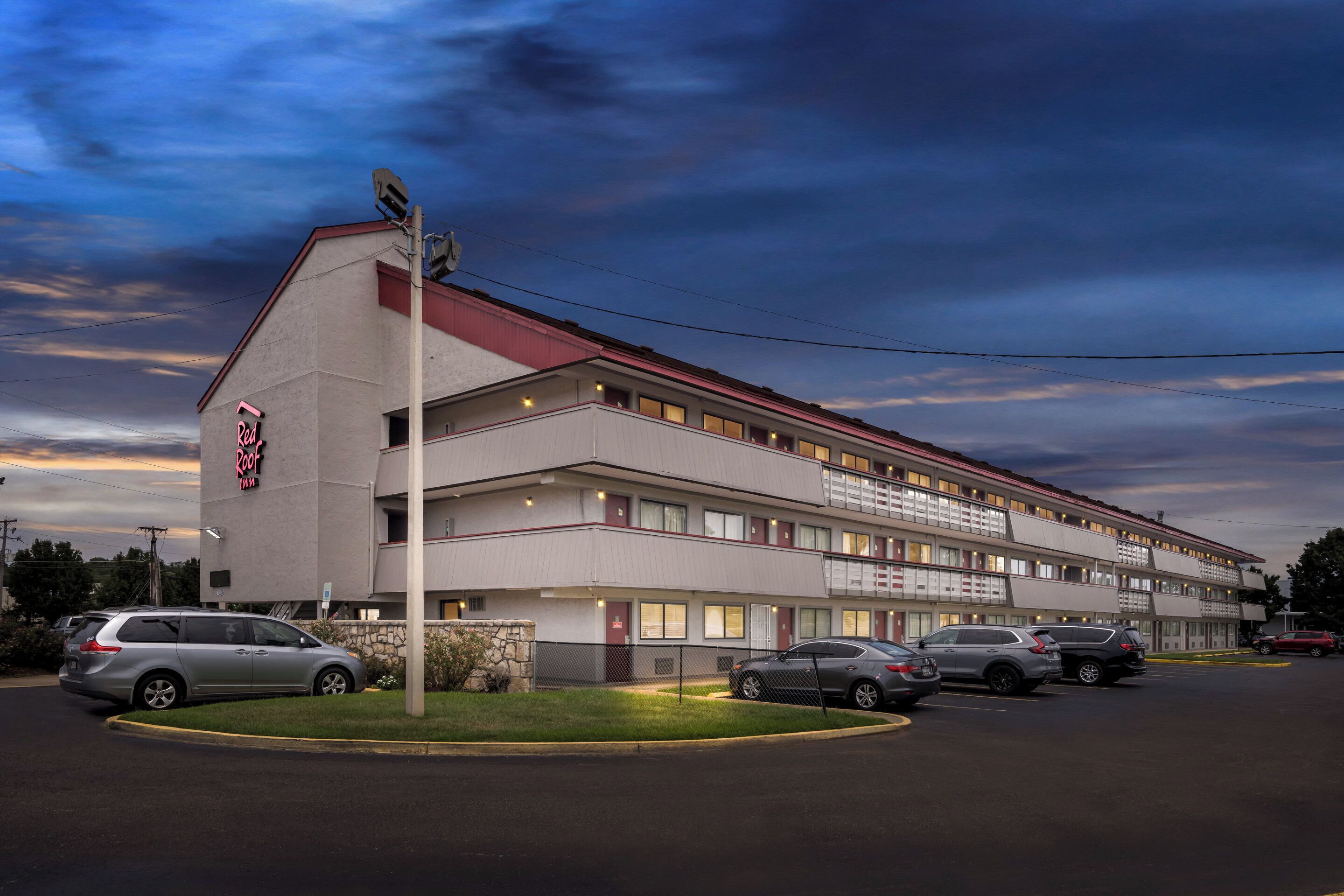A multi-story motel with a red roof and a sign that reads "Red Roof Inn."