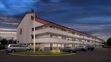 A multi-story motel with a red roof and a sign that reads "Red Roof Inn."