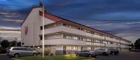 Un motel de varios pisos con techo rojo y un letrero que dice 'Red Roof Inn'.