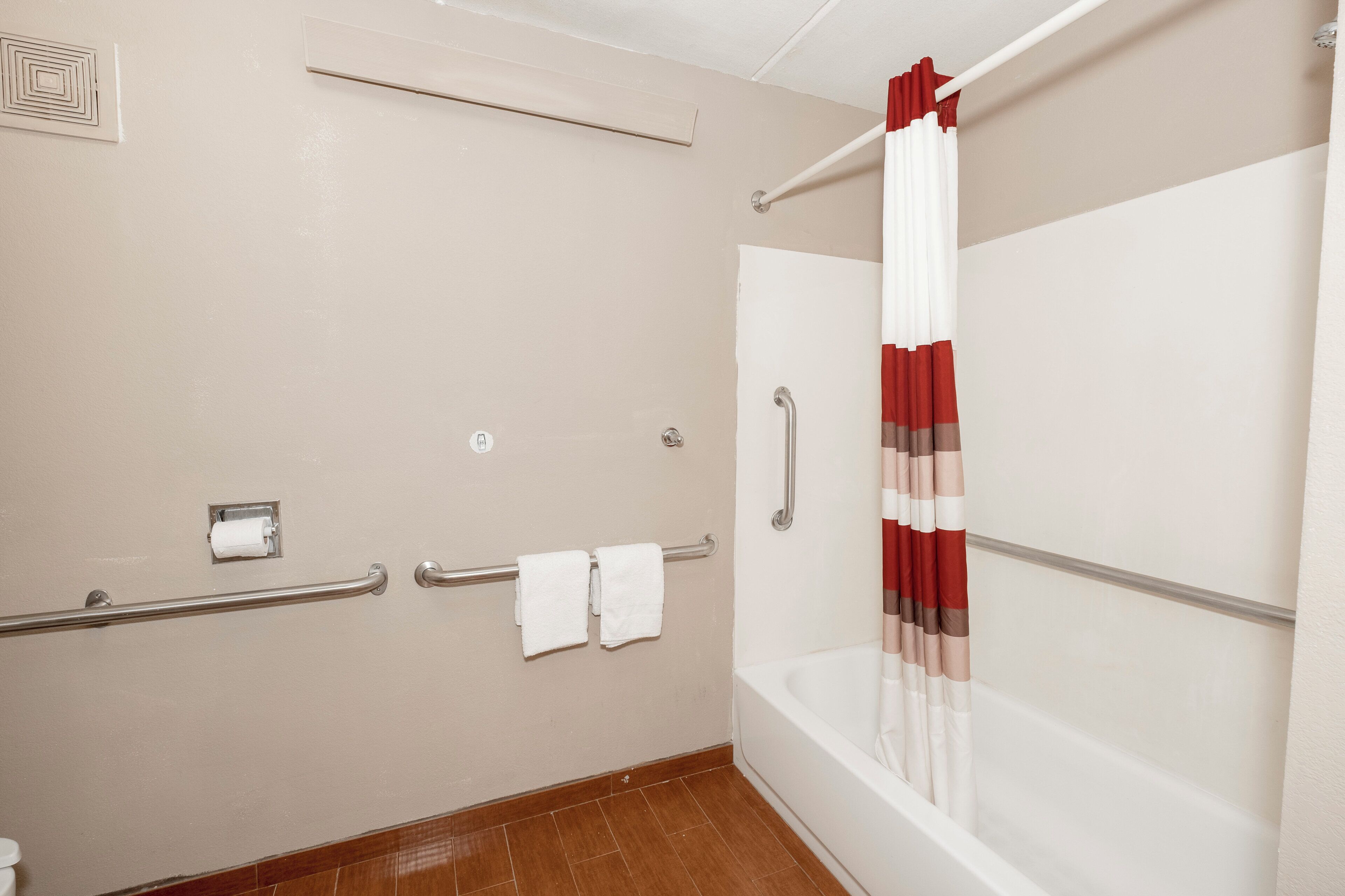 Une salle de bain équipée d’une baignoire, d’un rideau de douche et d’une barre d’appui.