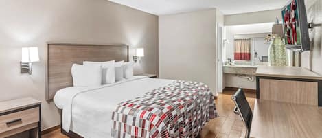 A hotel room with a large bed, bedside tables, a desk, and a TV.