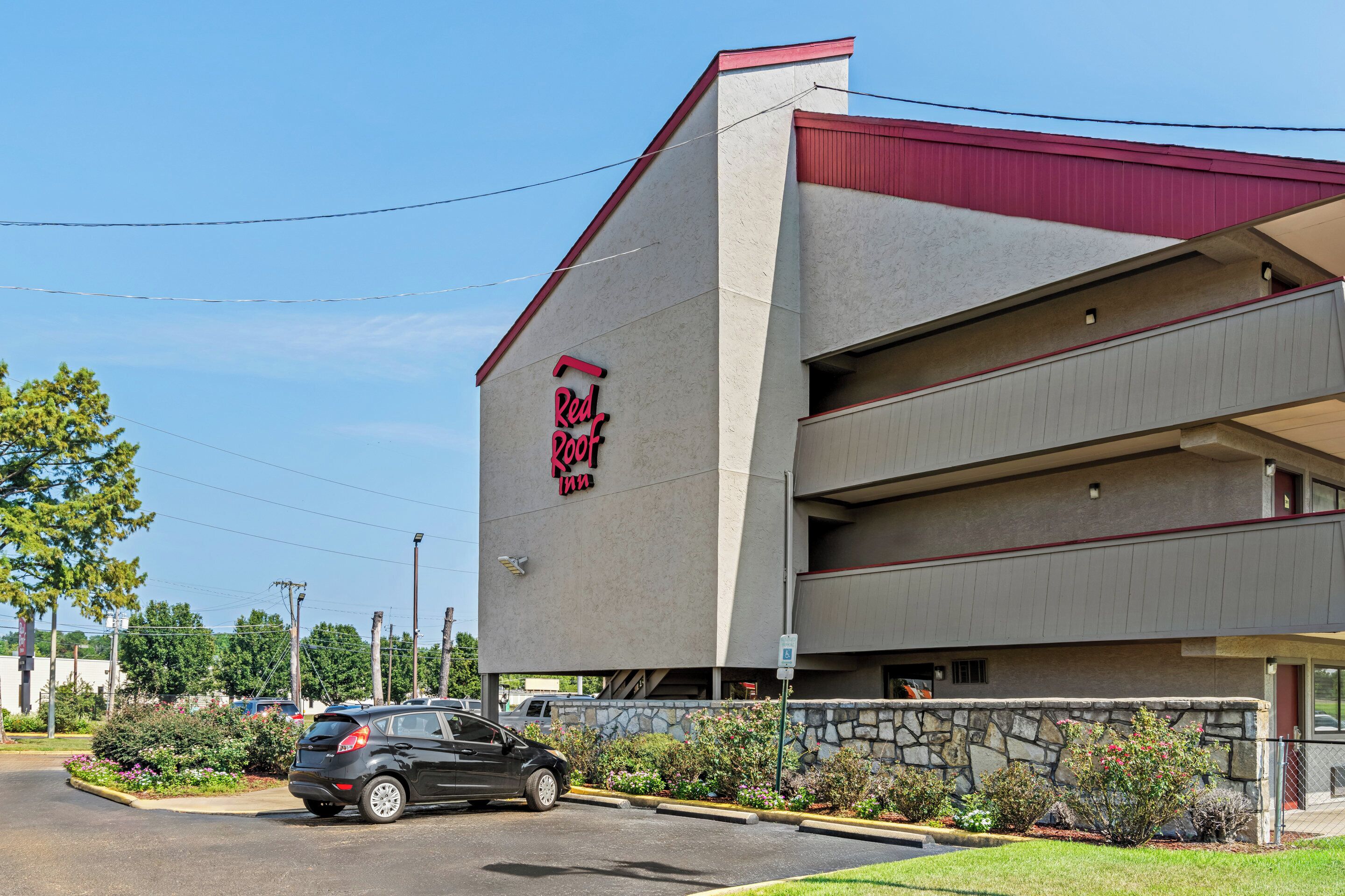 A Red Roof Inn with a modern design, featuring a stone facade and a parking lot.