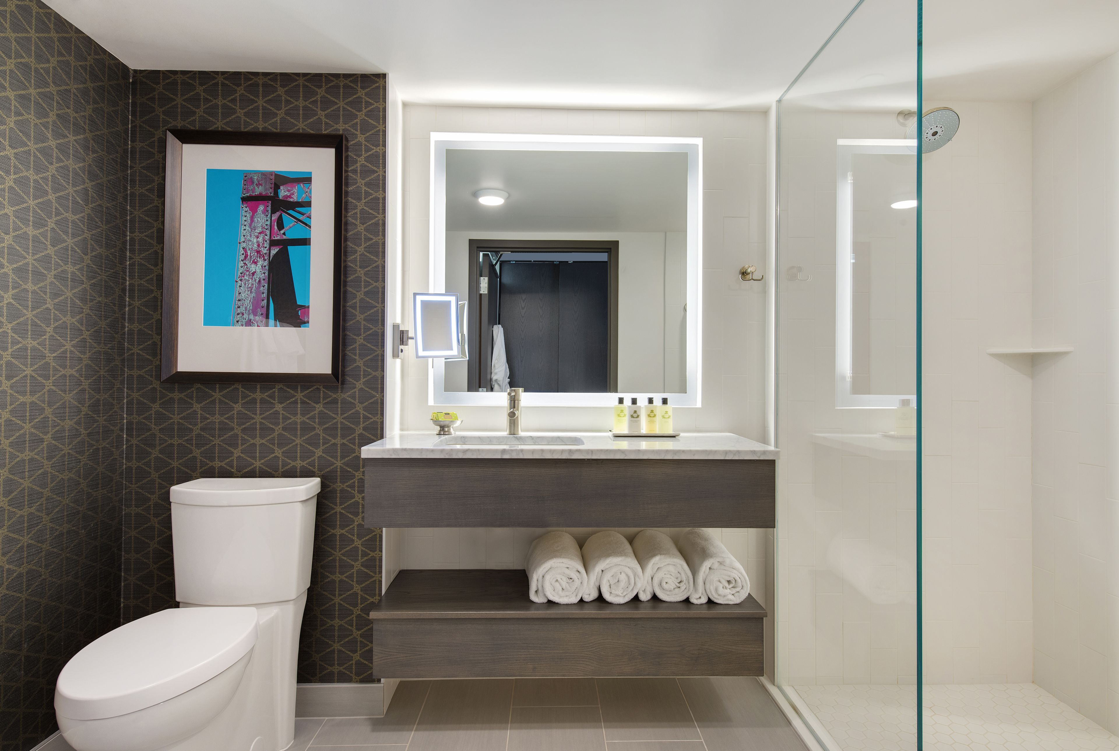 Ein modernes Badezimmer mit Toilette, Waschbecken mit Spiegel und Duschbereich.