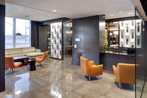 A modern lobby with a reception desk, seating area, and a glass partition. - InterContinental Saint Paul Riverfront by IHG (St. Paul)