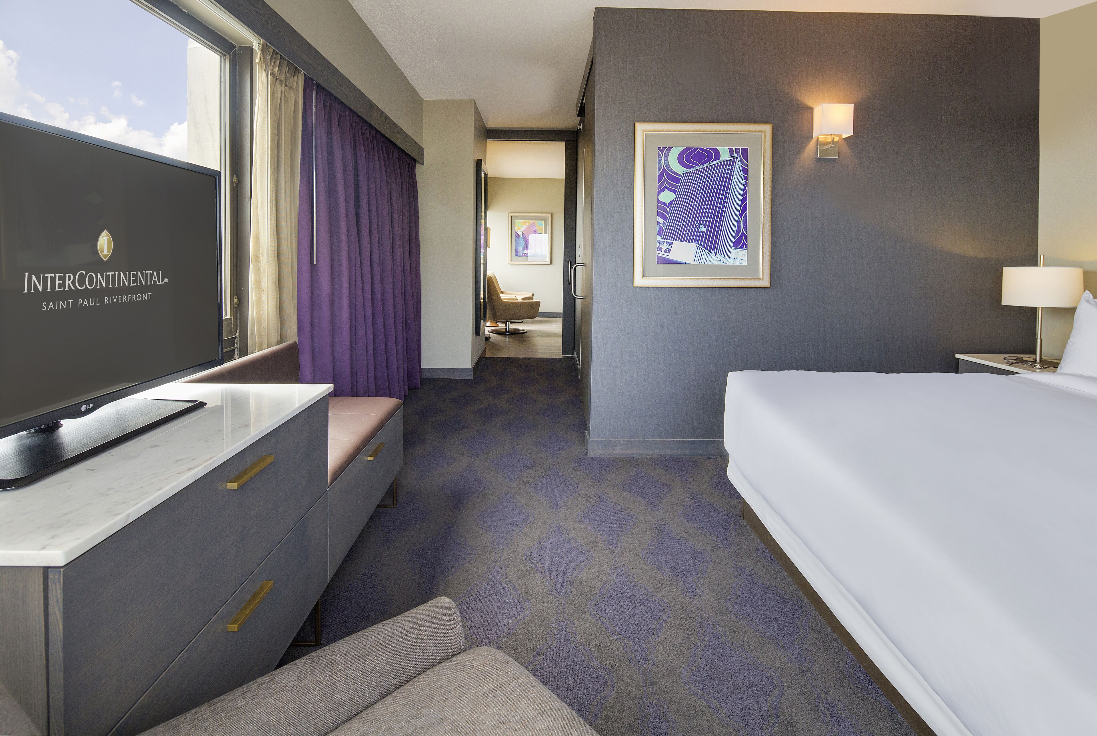 A hotel room with a bed, a TV, a desk, and a chair.