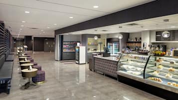 Un interior moderno con una vitrina de panadería, un área de asientos y una barra con varios artículos.