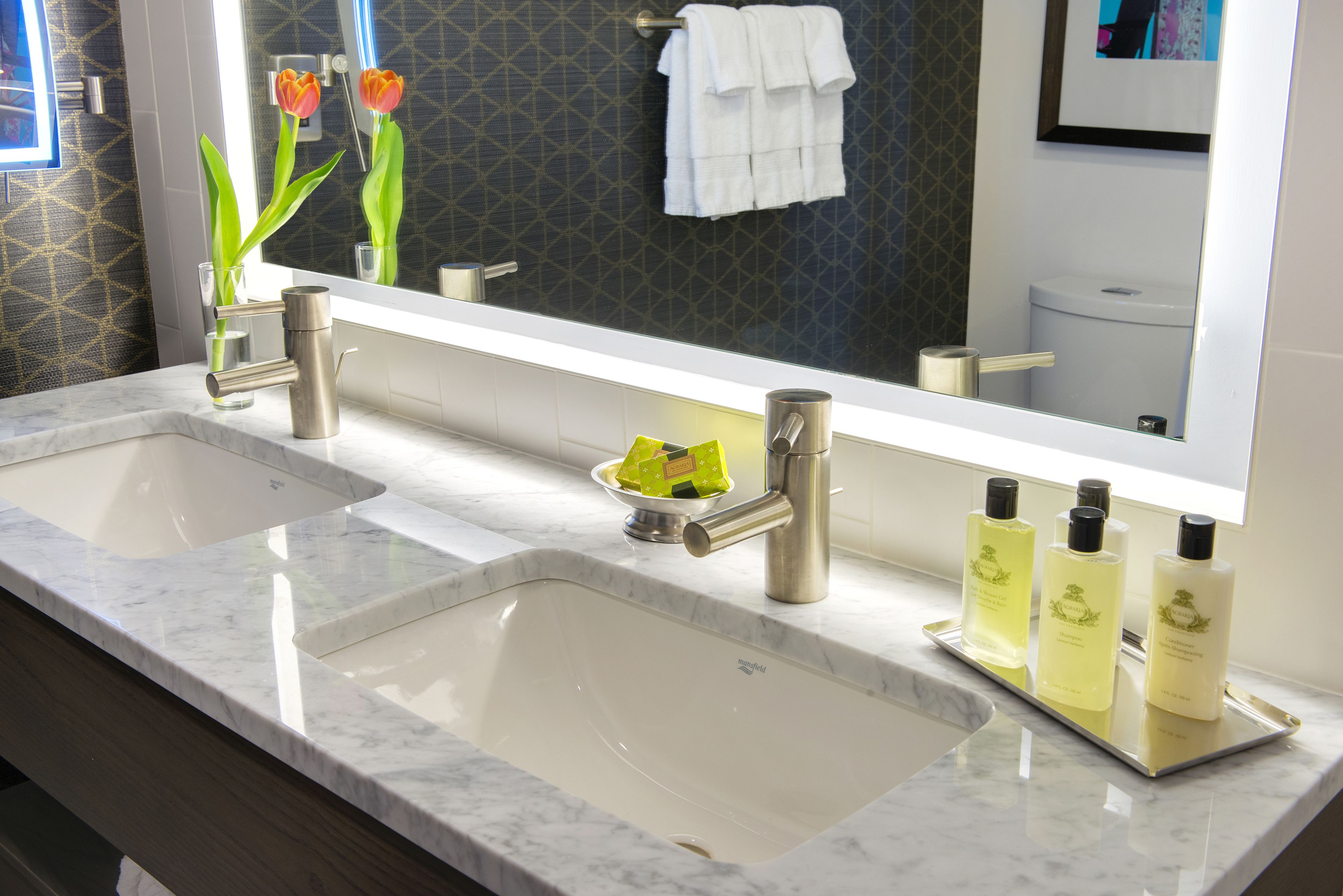 Une salle de bain avec deux lavabos, un miroir et un plateau contenant des articles de toilette.