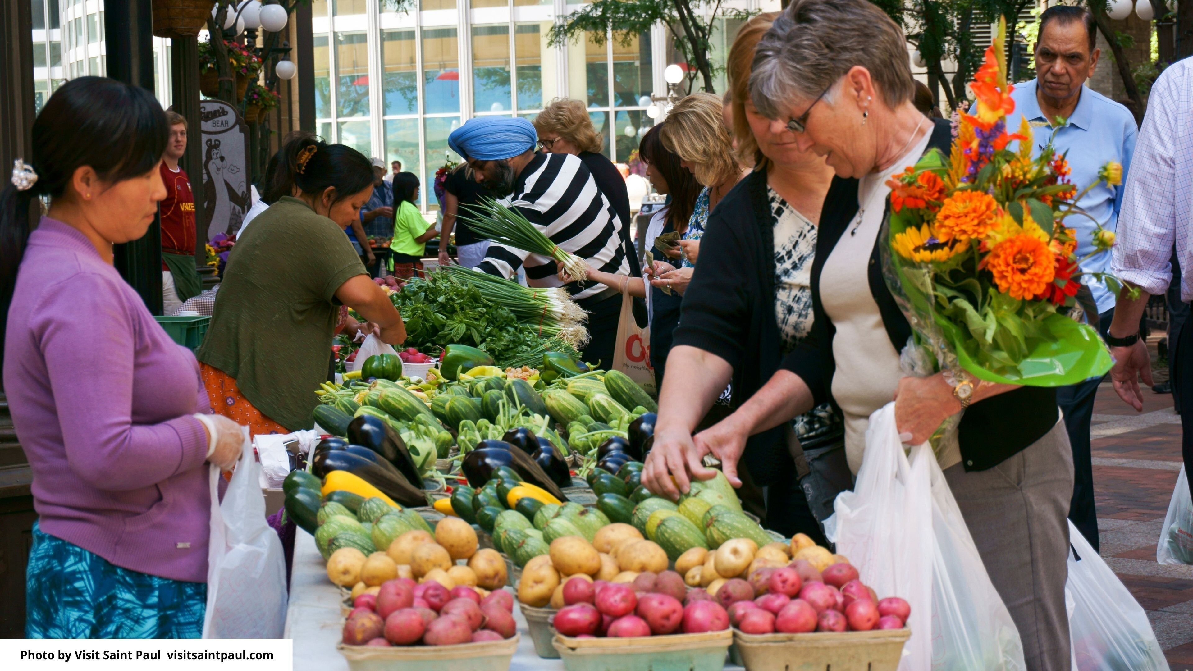 Un marché animé en plein air où l’on vend une grande variété de produits frais et de fleurs.