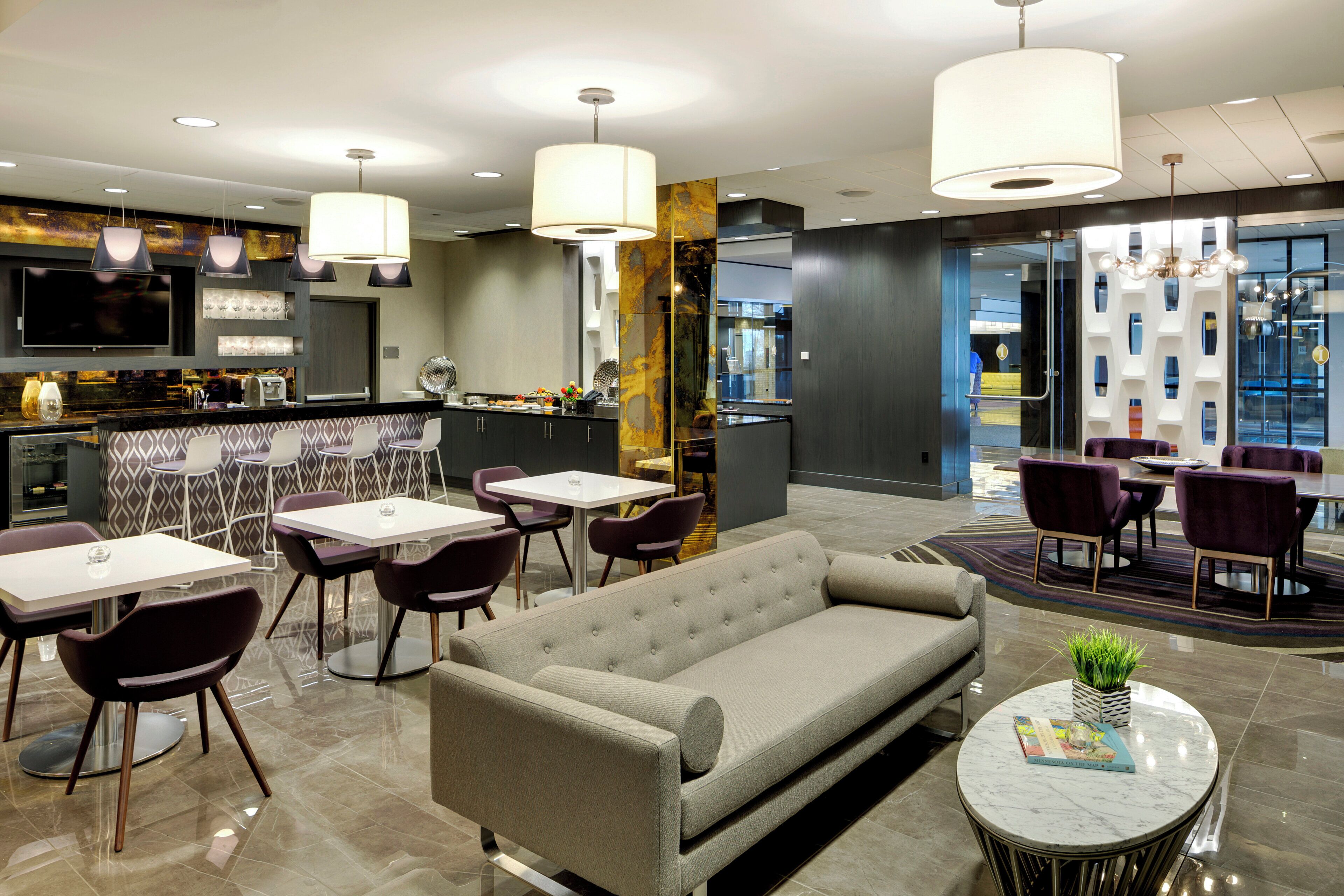 Un moderno vestíbulo de hotel con zona de bar, asientos y un amplio ventanal con vistas.