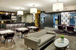 A modern hotel lobby with a bar area, seating arrangements, and a large window offering a view. - InterContinental Saint Paul Riverfront by IHG (St. Paul)