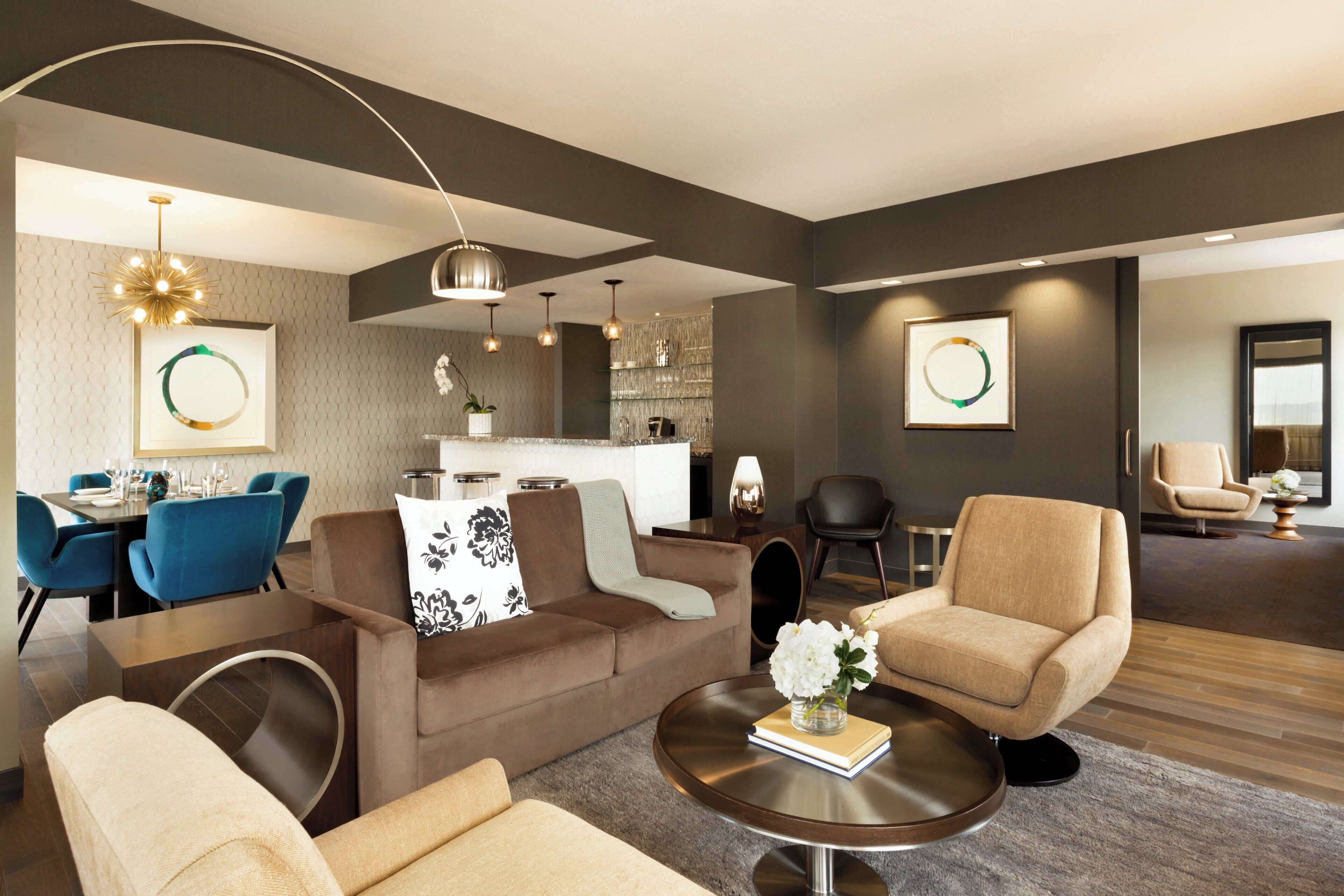 A modern living room with a sofa, armchairs, a coffee table, and a dining area with chairs and a table.