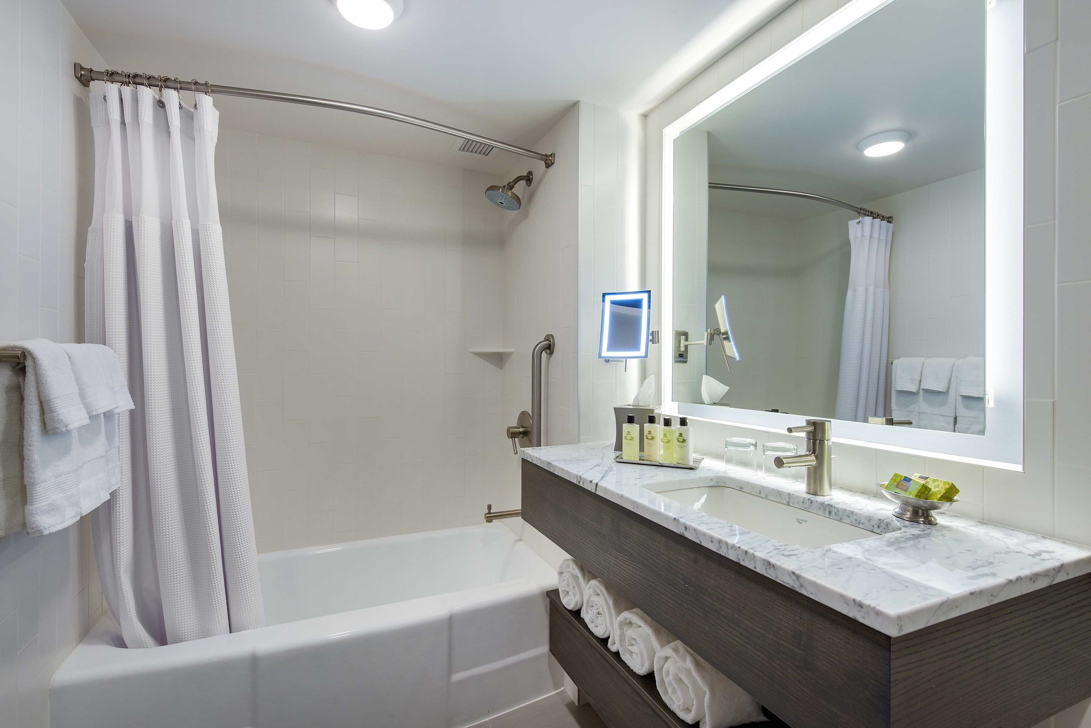 Un baño moderno con bañera, ducha y tocador con espejo.