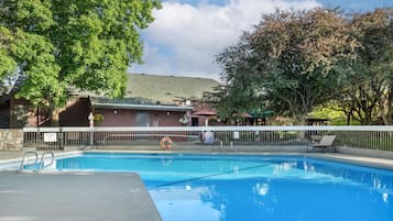 Una piscina al aire libre de temporada, sombrillas