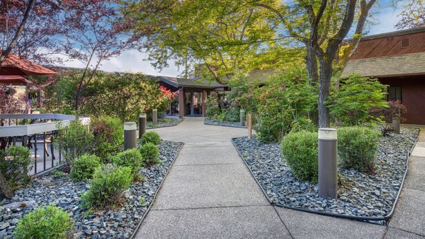 A pathway leading to a building with a covered entrance, surrounded by landscaped gardens and trees. - Best Western Sunridge Inn & Conference Center (Baker City)