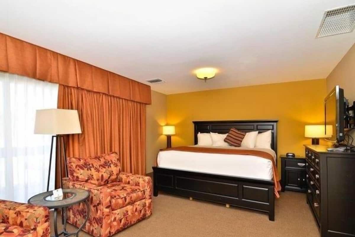 Une chambre d’hôtel comprenant un lit, deux lampes de chevet, un canapé, une petite table et une commode.